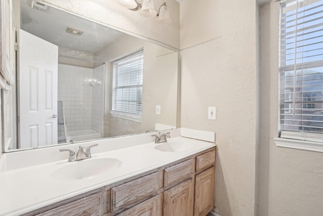 bathroom featuring visible vents, a sink, a textured wall, and double vanity