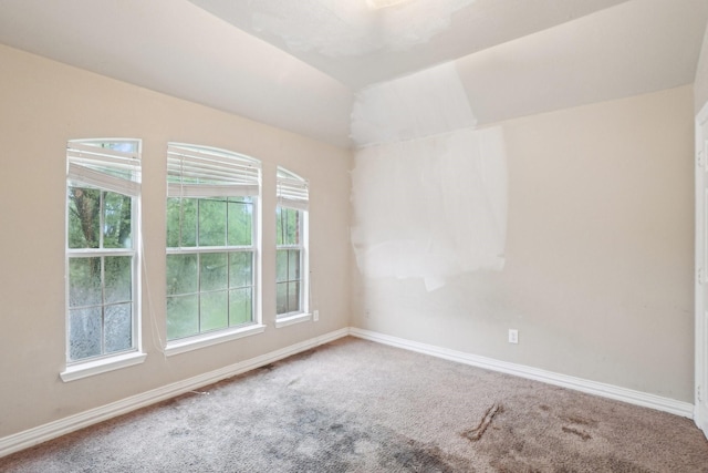 carpeted spare room featuring baseboards and lofted ceiling