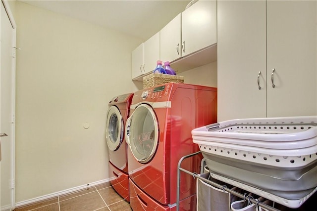 washroom featuring separate washer and dryer, cabinet space, light tile patterned floors, and baseboards