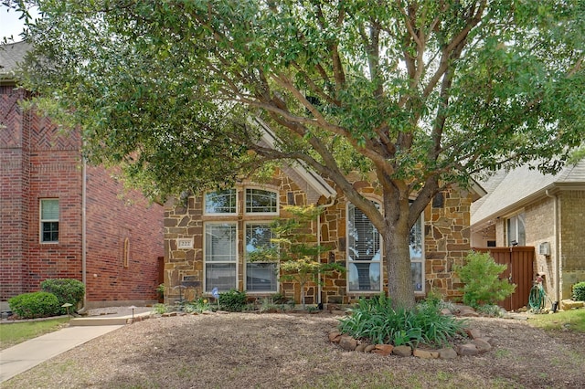 view of front of house featuring stone siding and fence