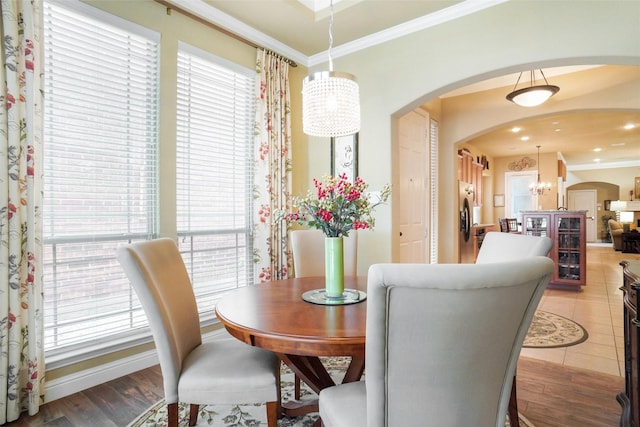dining room featuring arched walkways, crown molding, a chandelier, and light wood-type flooring