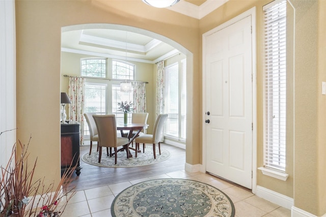 foyer entrance with arched walkways, crown molding, healthy amount of natural light, light tile patterned flooring, and baseboards