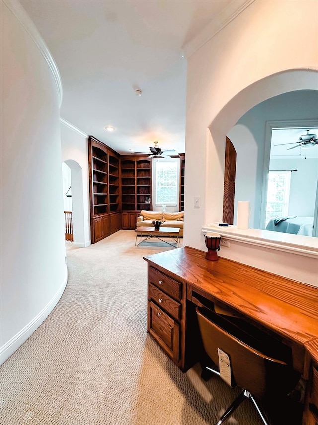 home office featuring arched walkways, a ceiling fan, ornamental molding, light carpet, and built in shelves