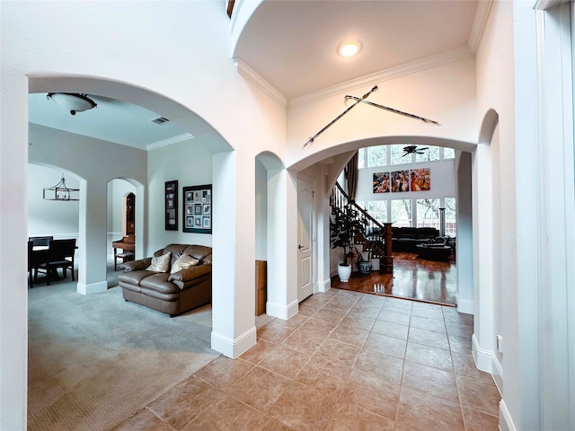 hall featuring ornamental molding, baseboards, stairs, light tile patterned floors, and light colored carpet