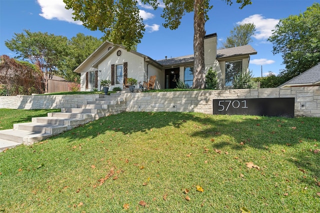 exterior space with brick siding, a front lawn, fence, and a chimney