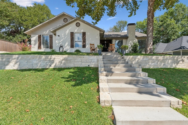 bungalow-style home featuring brick siding, fence, a chimney, and a front yard