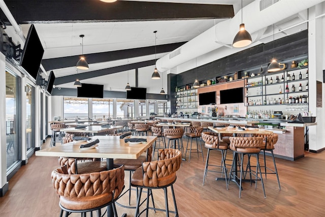 dining area with visible vents, lofted ceiling with beams, wood finished floors, and a community bar