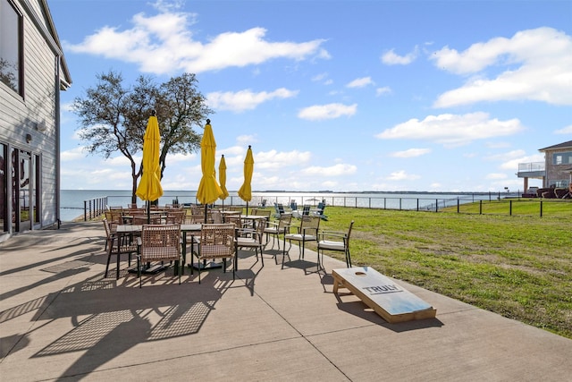 view of patio with outdoor dining area, a water view, and fence