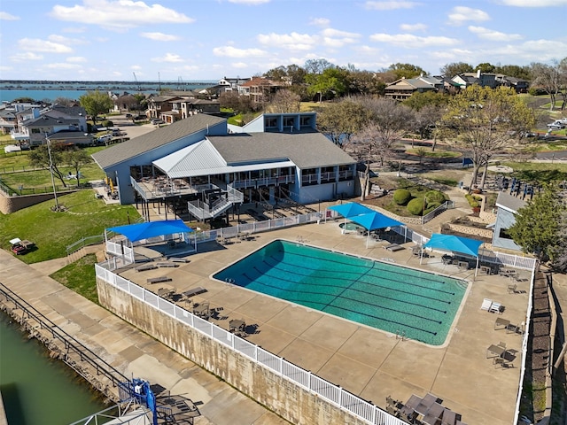 pool with a water view, fence, and a patio