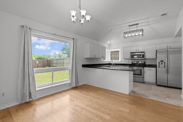 kitchen with dark countertops, a notable chandelier, appliances with stainless steel finishes, a sink, and vaulted ceiling