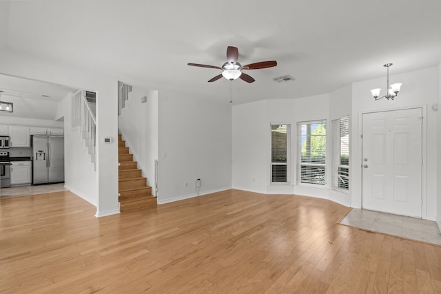 unfurnished living room with visible vents, baseboards, stairway, light wood-type flooring, and ceiling fan with notable chandelier