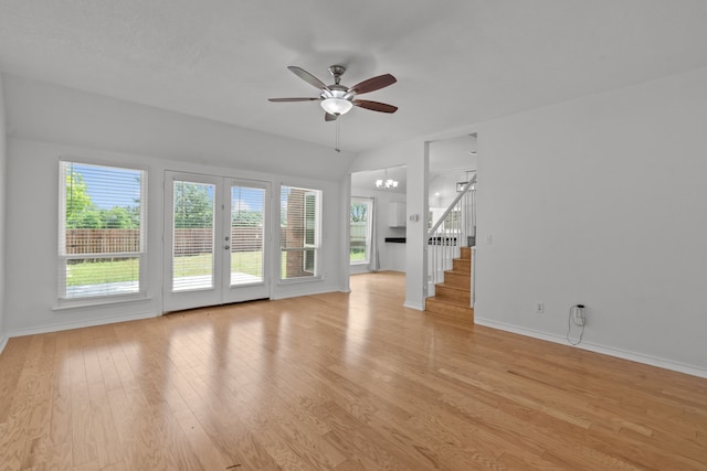 unfurnished living room with stairs, baseboards, ceiling fan with notable chandelier, and light wood-type flooring