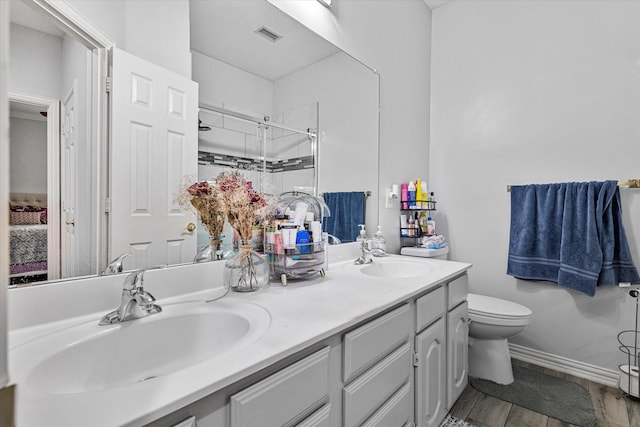 full bath featuring a sink, a shower stall, toilet, and double vanity
