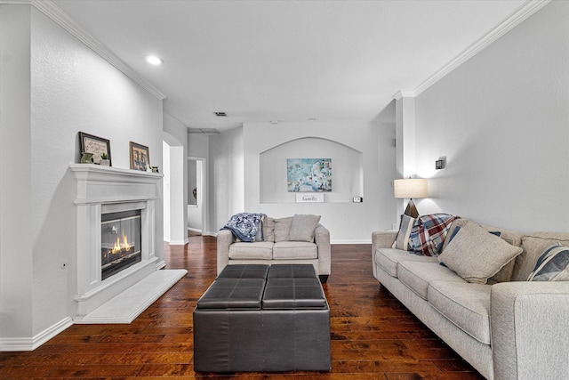 living room with ornamental molding, a glass covered fireplace, baseboards, recessed lighting, and hardwood / wood-style flooring