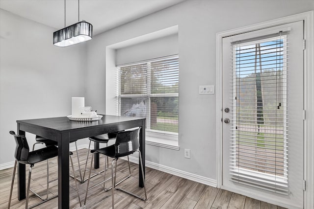 dining space featuring baseboards, plenty of natural light, and light wood finished floors