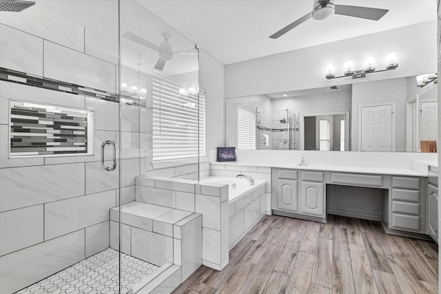 bathroom featuring ceiling fan, a bath, a stall shower, wood finished floors, and vanity