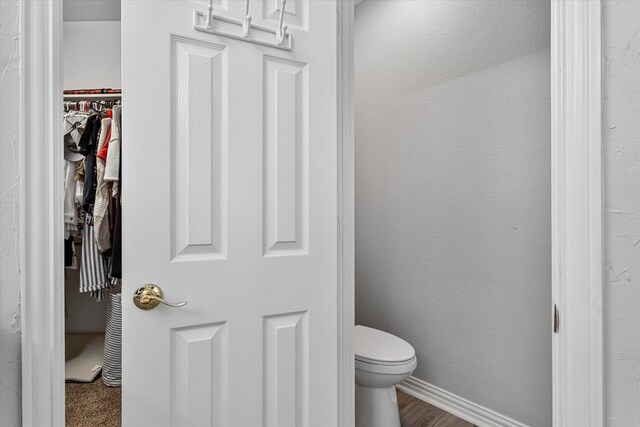 bathroom with toilet and a walk in closet