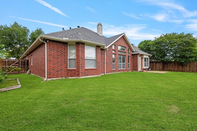 back of house featuring a fenced backyard, a chimney, and a yard