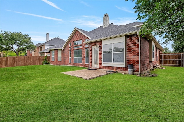 back of house featuring a yard, brick siding, a patio, and a fenced backyard
