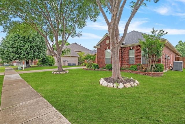 view of front of house featuring brick siding, a shingled roof, central air condition unit, and a front yard
