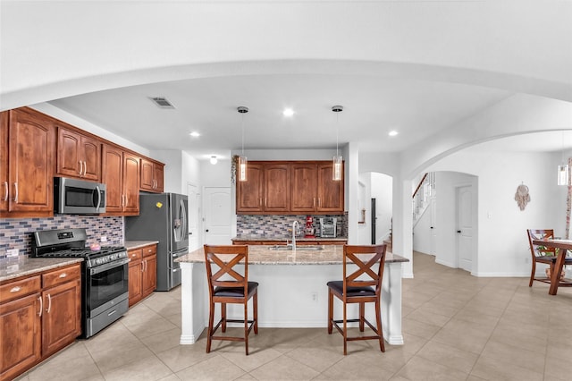 2317 Willard Dr, Mckinney, TX 75072 - kitchen featuring stainless steel appliances, a sink, arched walkways, backsplash, and a breakfast bar area
