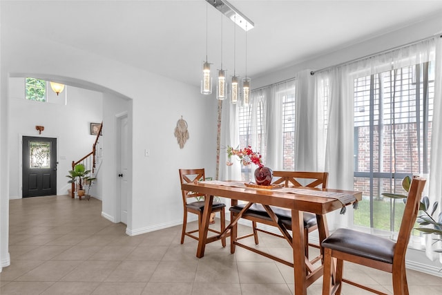 2317 Willard Dr, Mckinney, TX 75072 - dining space featuring baseboards, arched walkways, light tile patterned flooring, and stairway