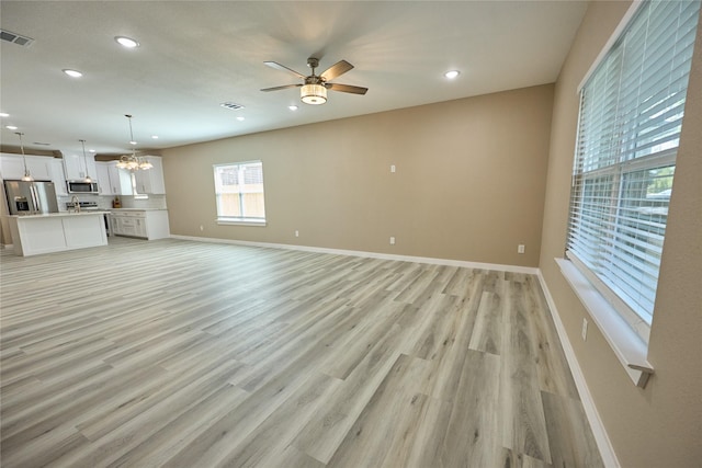 unfurnished living room featuring recessed lighting, ceiling fan, light wood-type flooring, baseboards, and a chandelier