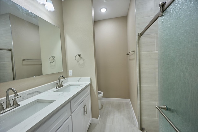 full bathroom with toilet, baseboards, tiled shower, and double vanity