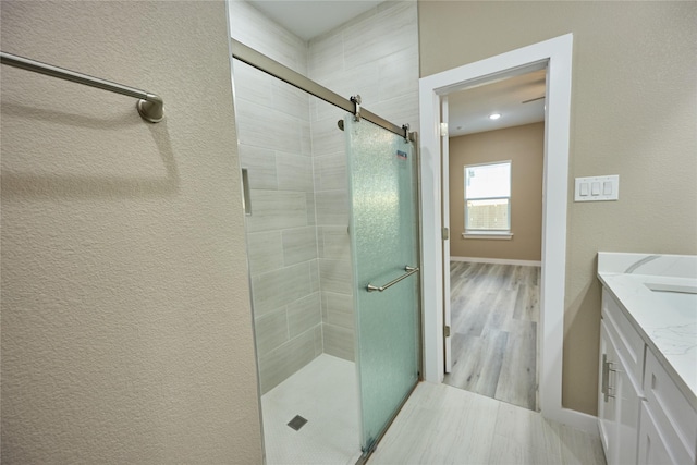 bathroom with a shower stall, vanity, and baseboards