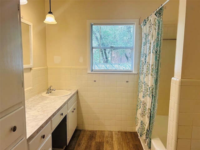 full bath featuring tile walls, wood finished floors, shower / tub combo, a wainscoted wall, and vanity