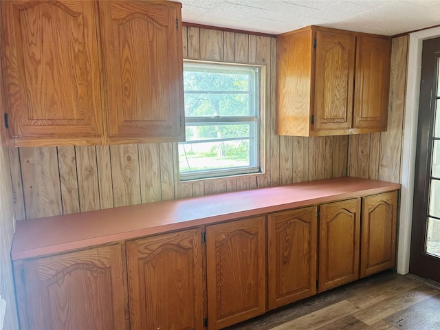 kitchen featuring light countertops, brown cabinetry, wood walls, and wood finished floors