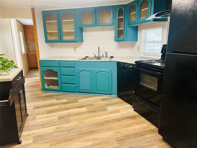 kitchen with decorative backsplash, light wood-type flooring, a sink, light countertops, and black appliances