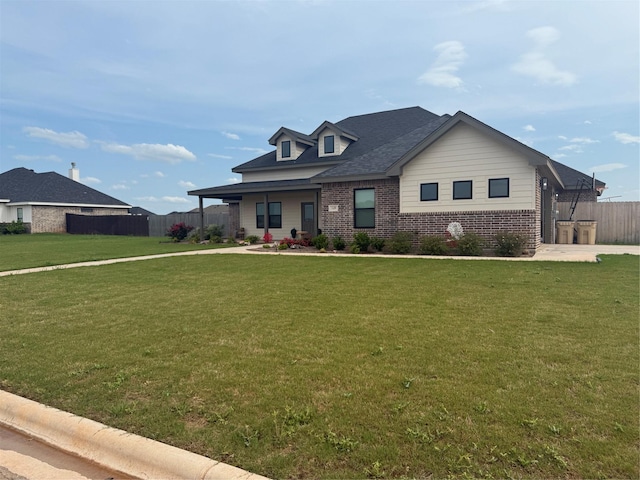 view of front of property with brick siding, fence, and a front yard