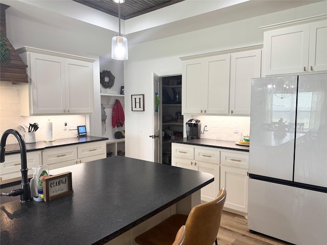 kitchen with freestanding refrigerator, white cabinetry, dark countertops, and tasteful backsplash