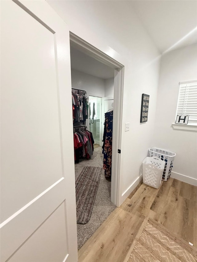 corridor with baseboards and wood finished floors