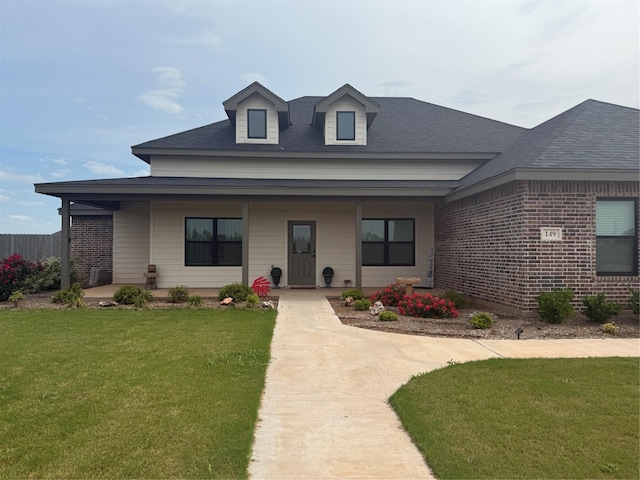 view of front of house featuring covered porch, roof with shingles, and a front lawn