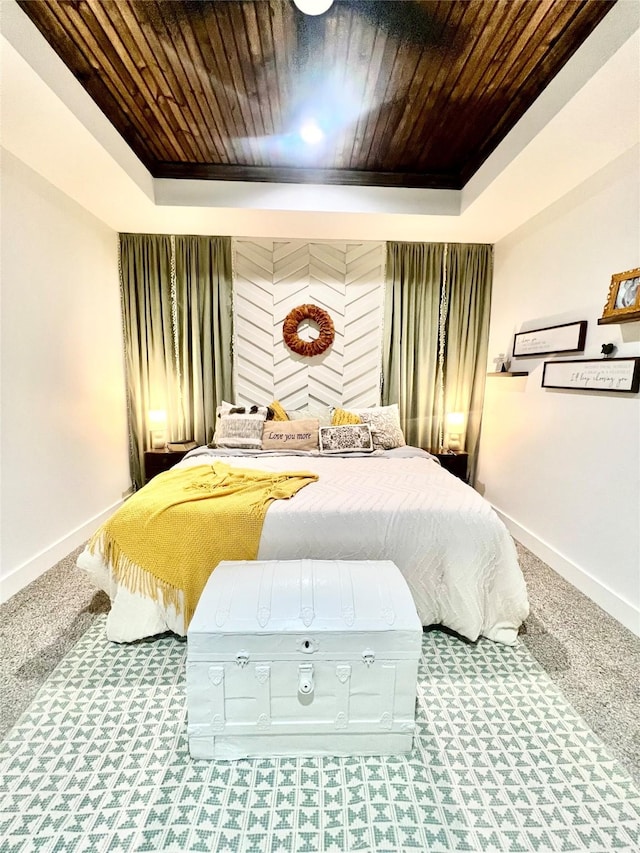 bedroom with baseboards, wood ceiling, and a tray ceiling