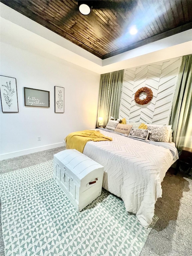 carpeted bedroom with baseboards, wood ceiling, and a tray ceiling