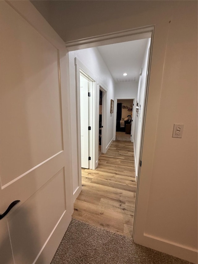 corridor with light wood finished floors, baseboards, and recessed lighting