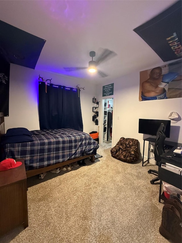 carpeted bedroom with a ceiling fan and an office area