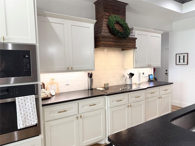 kitchen with stainless steel appliances, dark countertops, custom range hood, and tasteful backsplash