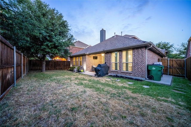10312 Flat Creek Trl, Mckinney, TX 75072 - back of house with brick siding, a fenced backyard, a chimney, a lawn, and a patio
