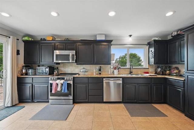 kitchen with crown molding, appliances with stainless steel finishes, a healthy amount of sunlight, and a sink