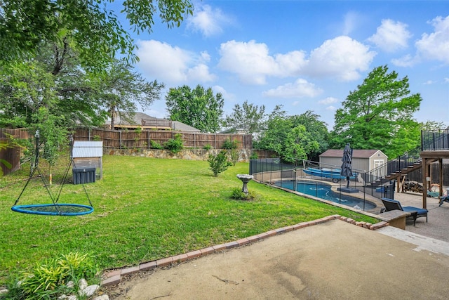 view of yard with a storage unit, a fenced backyard, a fenced in pool, an outbuilding, and a patio