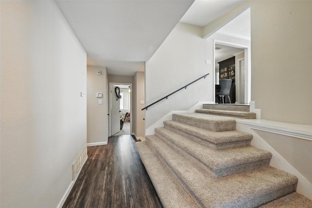 foyer with stairway, baseboards, wood finished floors, and visible vents