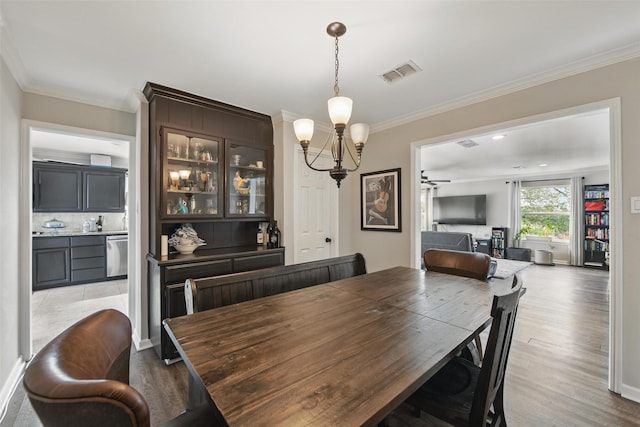 dining space with visible vents, ornamental molding, wood finished floors, baseboards, and a notable chandelier
