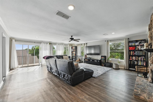 living area featuring a textured ceiling, visible vents, ornamental molding, and wood finished floors