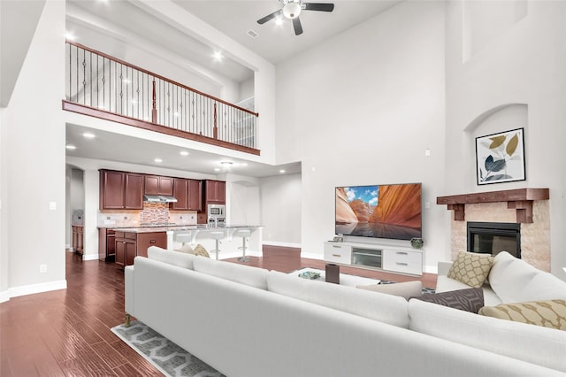 3020 Nyala Trl, Frisco, TX 75034 - living room with a ceiling fan, a towering ceiling, dark wood finished floors, baseboards, and a premium fireplace