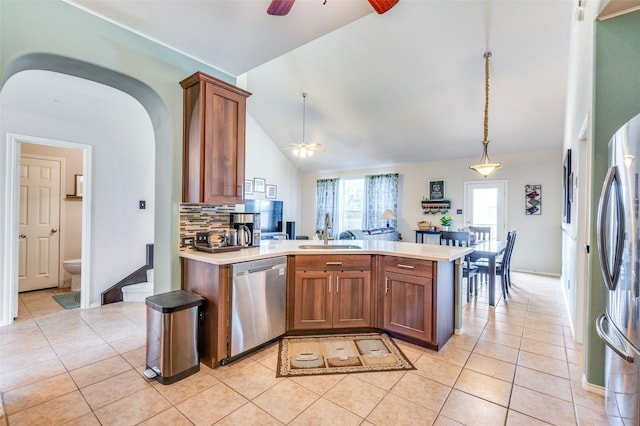 kitchen with a ceiling fan, a sink, light tile patterned floors, a peninsula, and stainless steel appliances