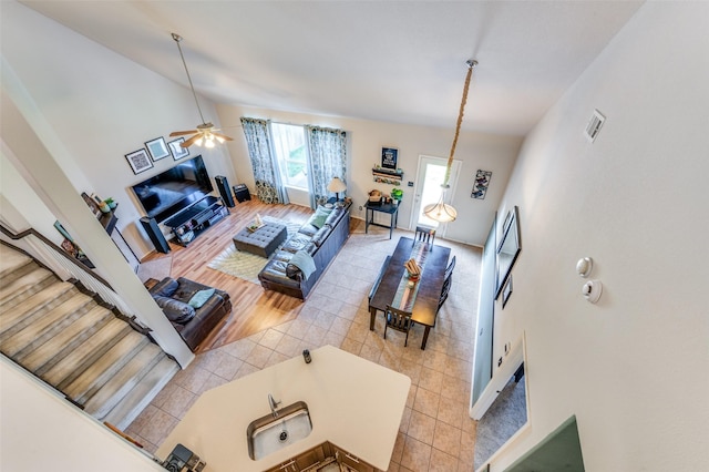 living area with baseboards, a ceiling fan, light tile patterned flooring, and lofted ceiling